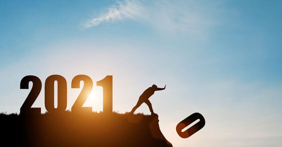 on the top of a hill are the number 2021 with an individual seemingly pushing "0" off the cliff. The depiction is that 2020 is being replaced by 2021