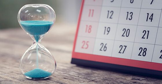 hourglass with blue sand and a desktop calendar