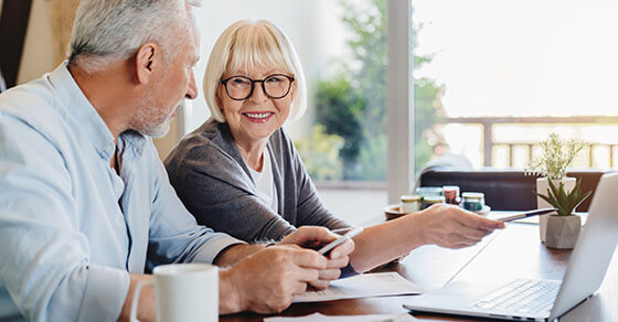 Senior couple doing home finances using laptop indoors