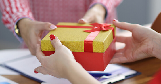 image of a wrapped box (gift) being passed from one person to another.