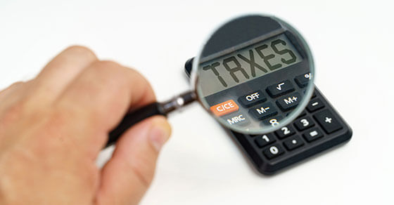 image of a calculator with a magnifying glass over the screen and the screen reading "TAXES"