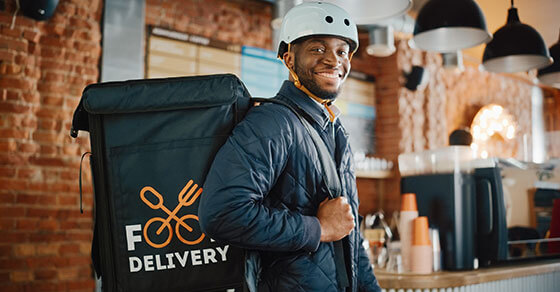 individual in a bike helmet carrying a food delivery bag.