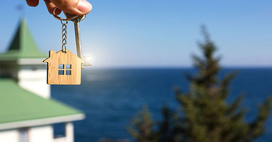image of a house keychain in the forefront and a water front property in the background.