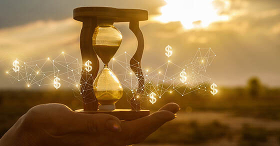 The concept of time and the new financial ideas. Hourglass in hand with and financial structure at sunset.