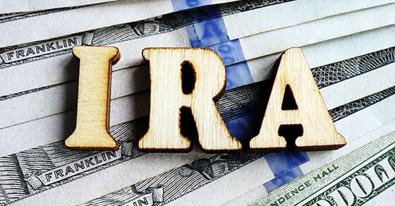 wooden letters that spell "IRA" on top of US bills