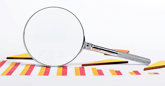 magnifying glass on top of paper with a graph.