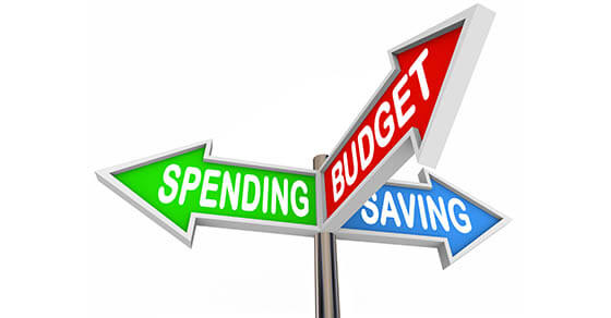 Three road signs pointing to Spending, Saving and Budget to symbolize budgeting and savings in your personal finance for long term financial goals or retirement