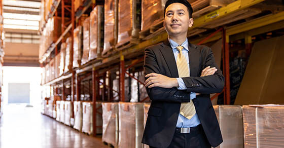 Portrait of asian confidence businessman investor stand in large factory and distribution warehouse environment. Business owner and investment concept.