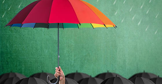 Life-health Insurance protection or business financial leadership concept with leader's hand holding rainbow umbrella on green chalkboard