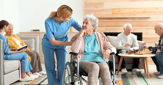 friendly nurse chatting with a smiling elderly woman in a wheelchair.