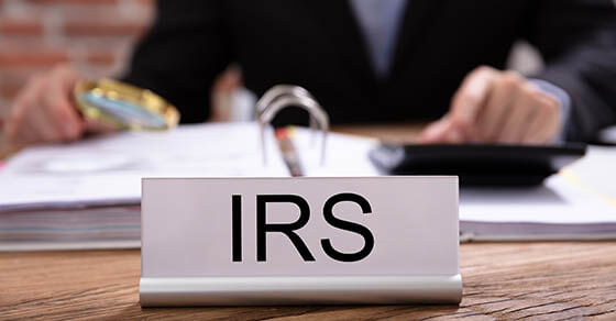 Nameplate With IRS Title Kept On Desk In Front Of Businessman Working In The Office