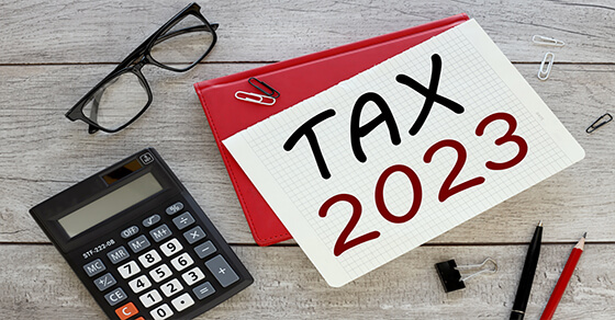 items on a desk including a calculator, glasses and a note that says "tax 2023"