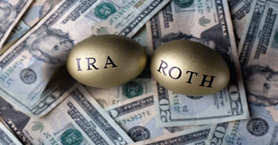 two gold eggs with "IRA" and "Roth" written on each, on top of a pile of bills.