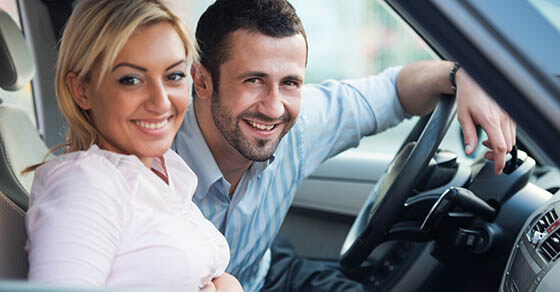 Smiling young couple posing sitting in a car