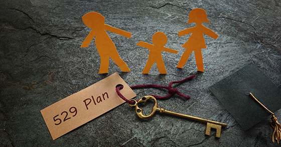 Image of a key on a table with the key tag that reads "529 plan" and a paper-cut out of a family next to the key.