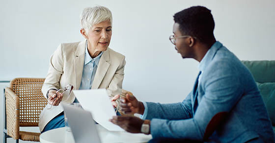 Mature entrepreneur and her African American coworker analyzing reports during business meeting in the office.