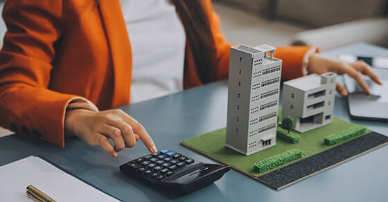 Close up realtor sit at table holds tiny house model, layout of cottage. Real estate purchase, new property, ownership, construction company make special offer to client, affordable dwelling concept