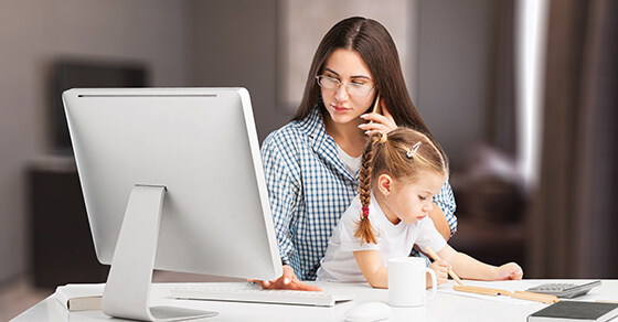 a mom working on a computer with a toddler on her lap. 