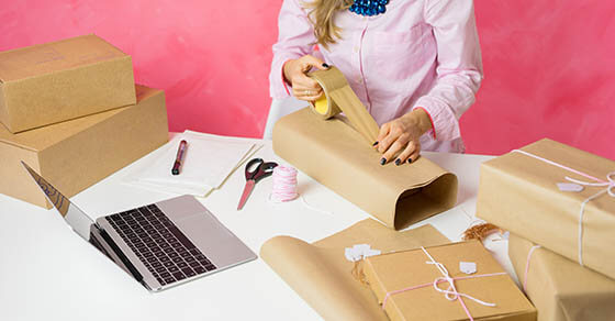 Woman selling items online and packaging goods for shipping.