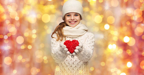 people, charity, holidays, children and love concept - smiling teenage girl in winter clothes with small red heart over lights background